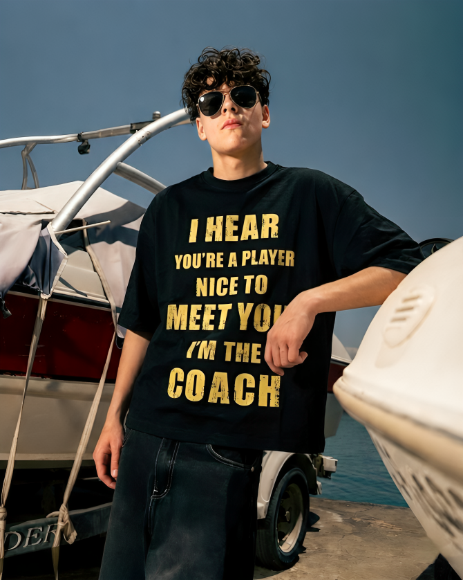 Person wearing a black t-shirt with yellow text by a boat