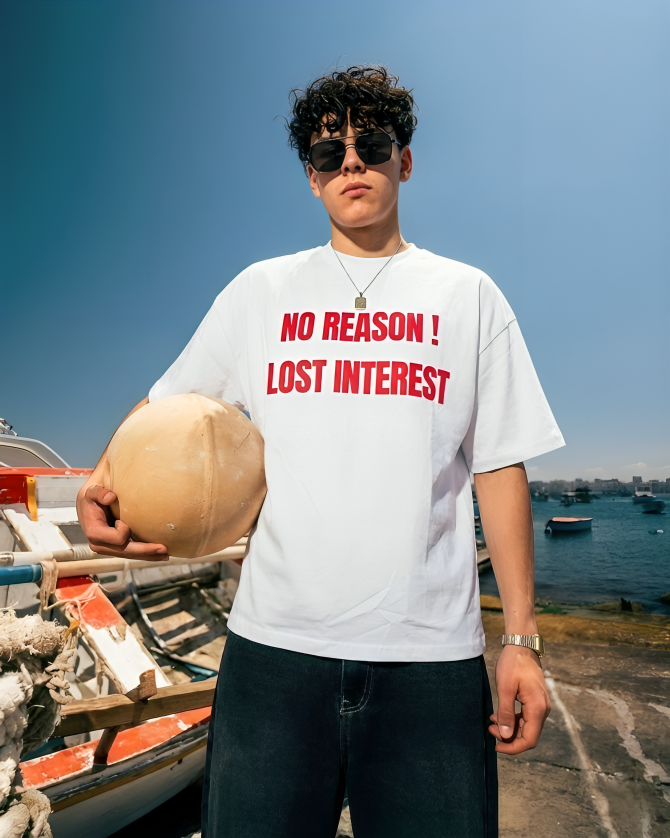 Person wearing a white t-shirt with red text by a waterfront