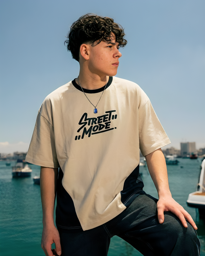 Person wearing a 'Street Mode' t-shirt by a waterfront with boats and buildings in the background.