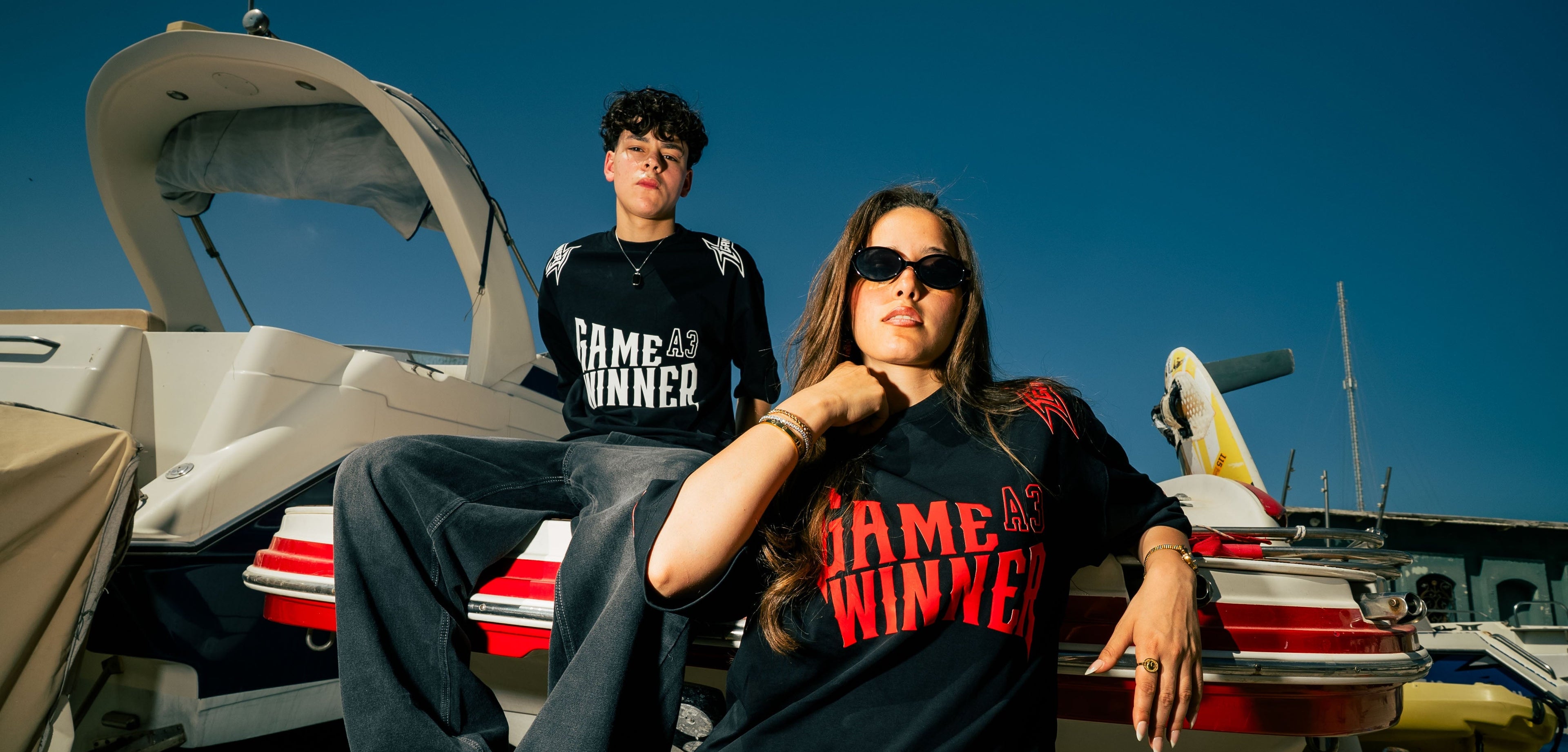 Two people wearing 'Game Winner' shirts on a boat.slider_item_iq96zU