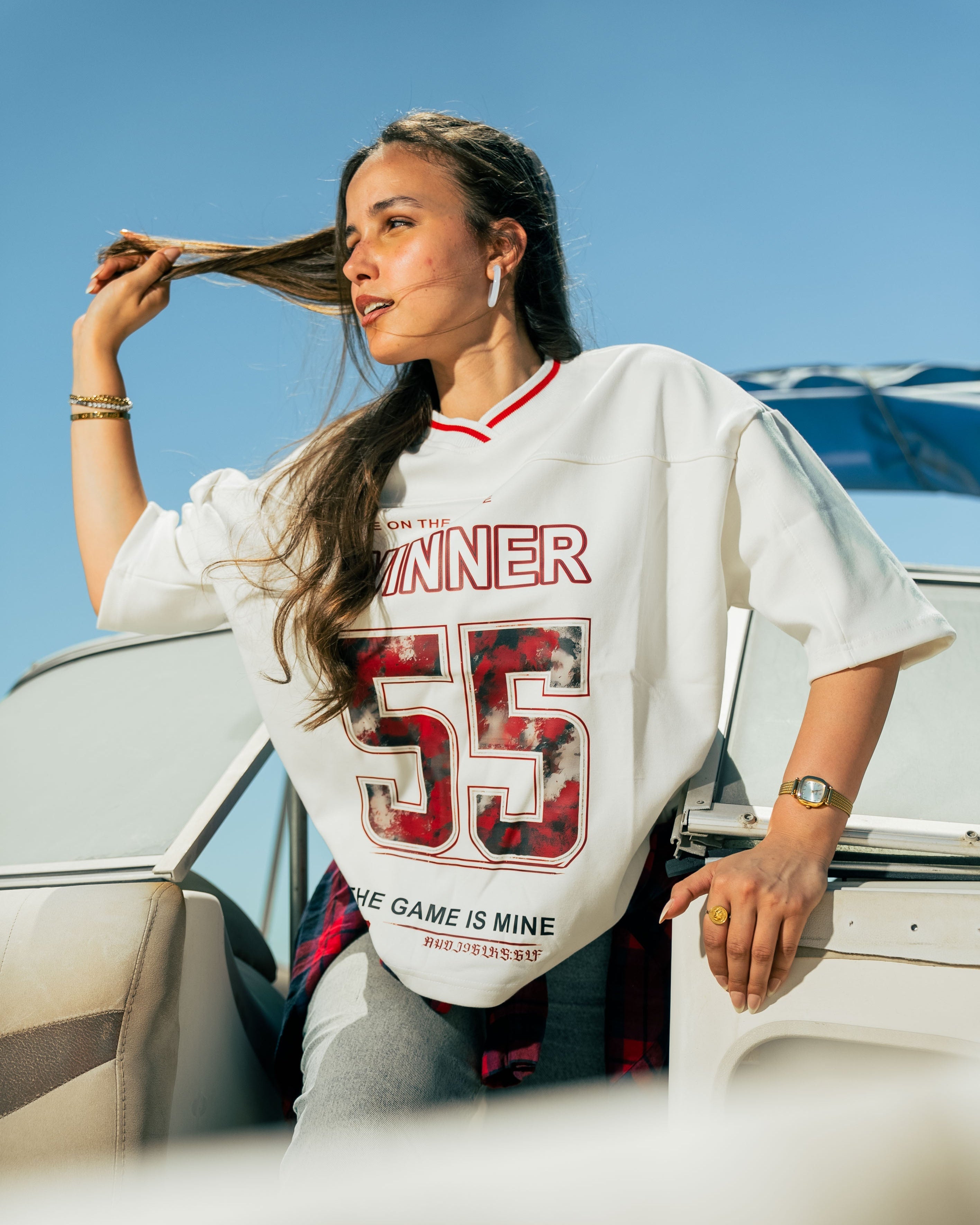 Woman wearing a white oversized t-shirt with red and black text and graphics, standing outdoors.