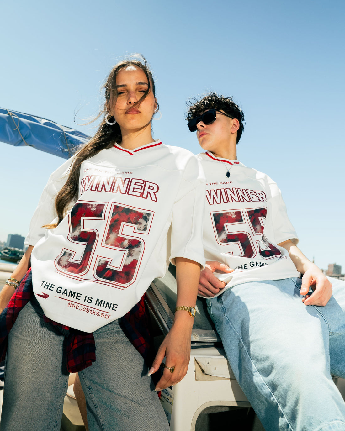 Woman wearing a white oversized t-shirt with red and black text and graphics, standing outdoors.