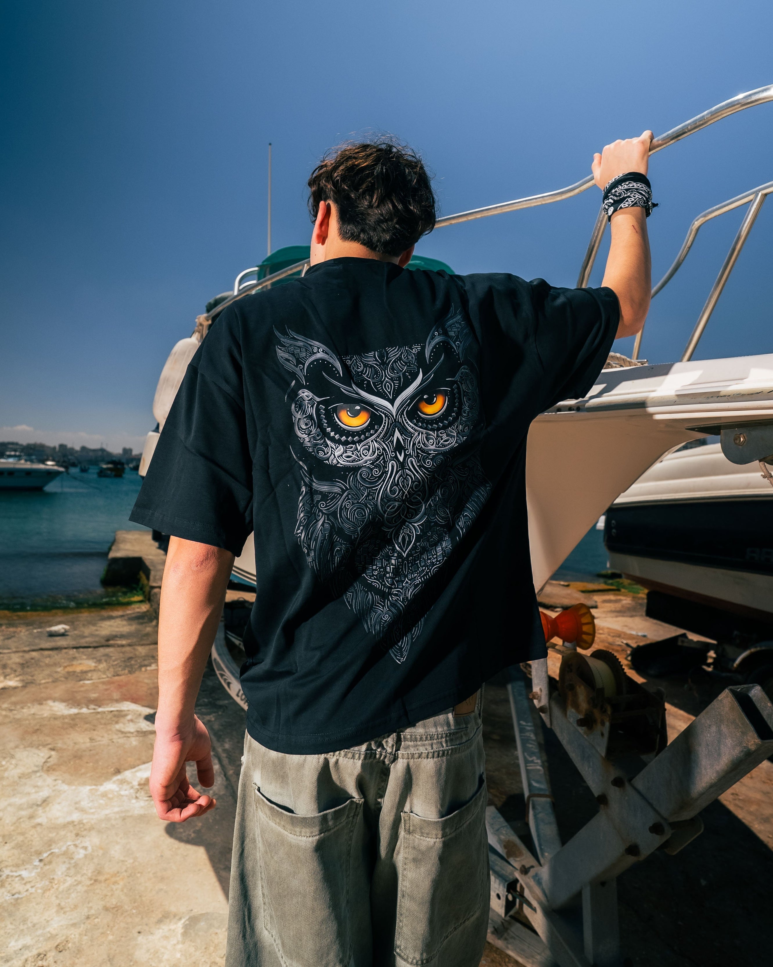 Person wearing a black t-shirt with an owl design on a boat