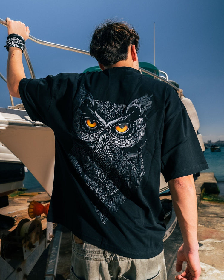 Person wearing a black t-shirt with an owl design on a boat