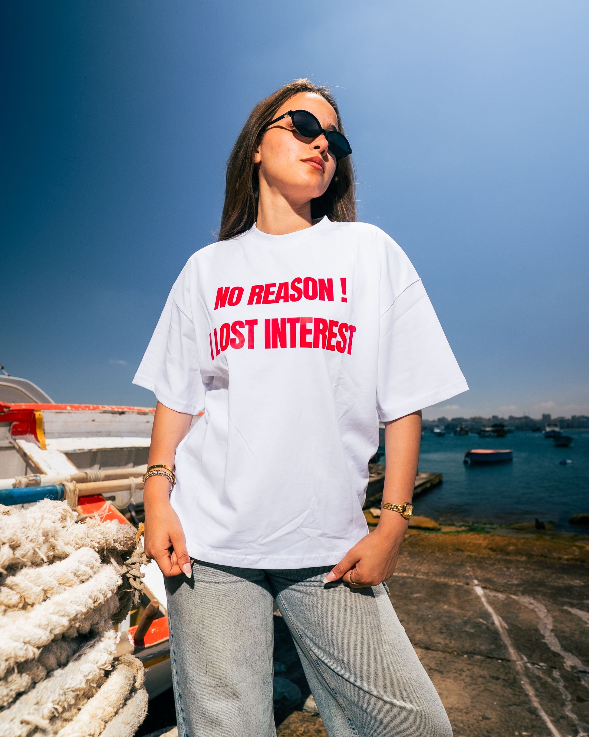 Person wearing a white t-shirt with red text by a waterfront