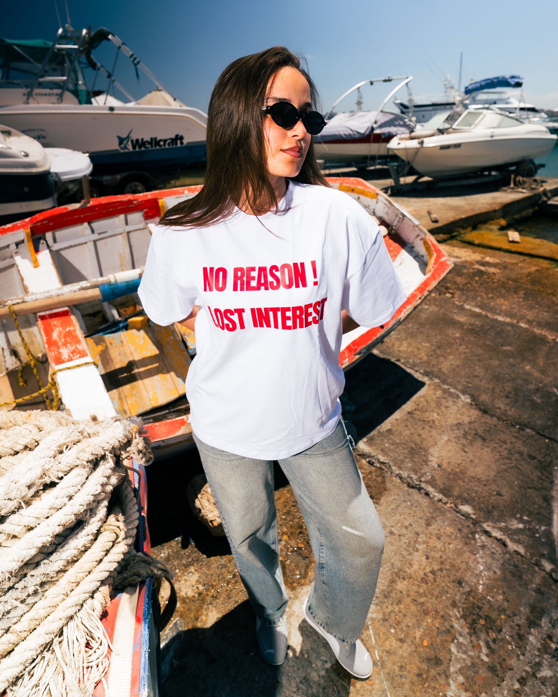 Person wearing a white t-shirt with red text at a marina