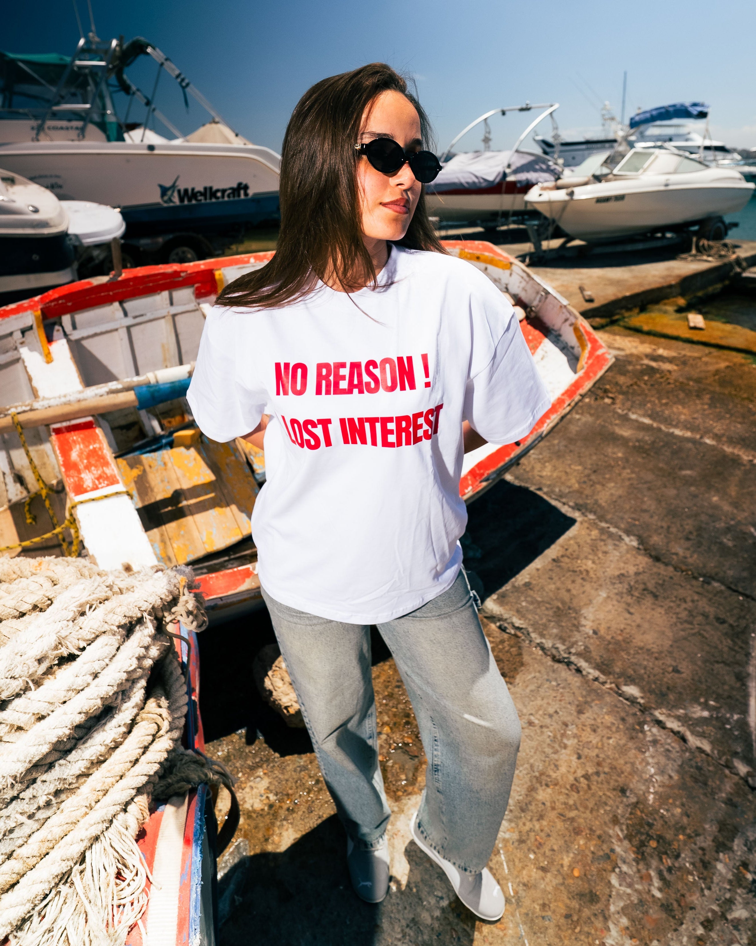 Person wearing a white t-shirt with red text at a marina