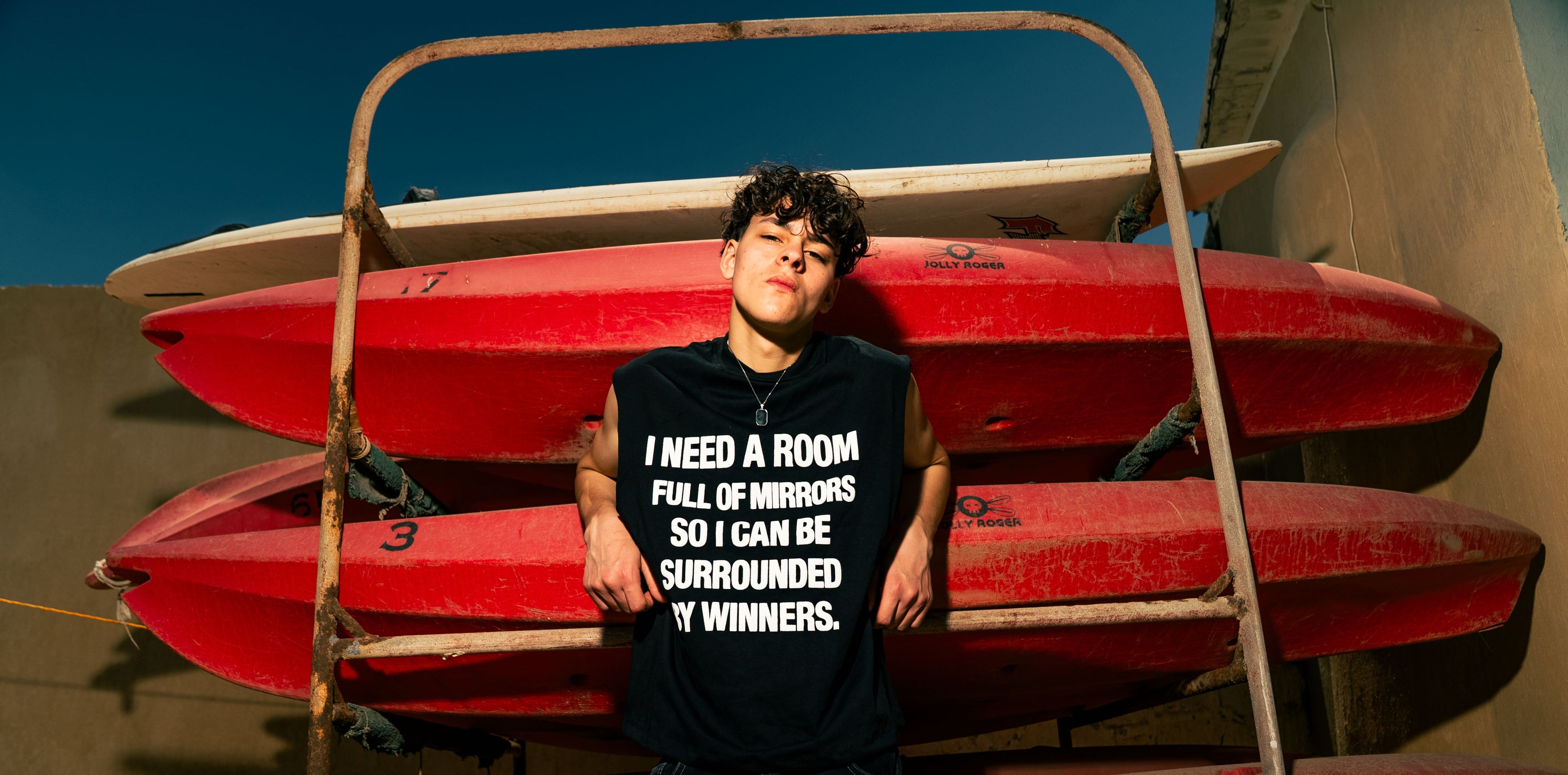 Person wearing a black t-shirt with text standing in front of red kayaks.slider_item_LpTCyb