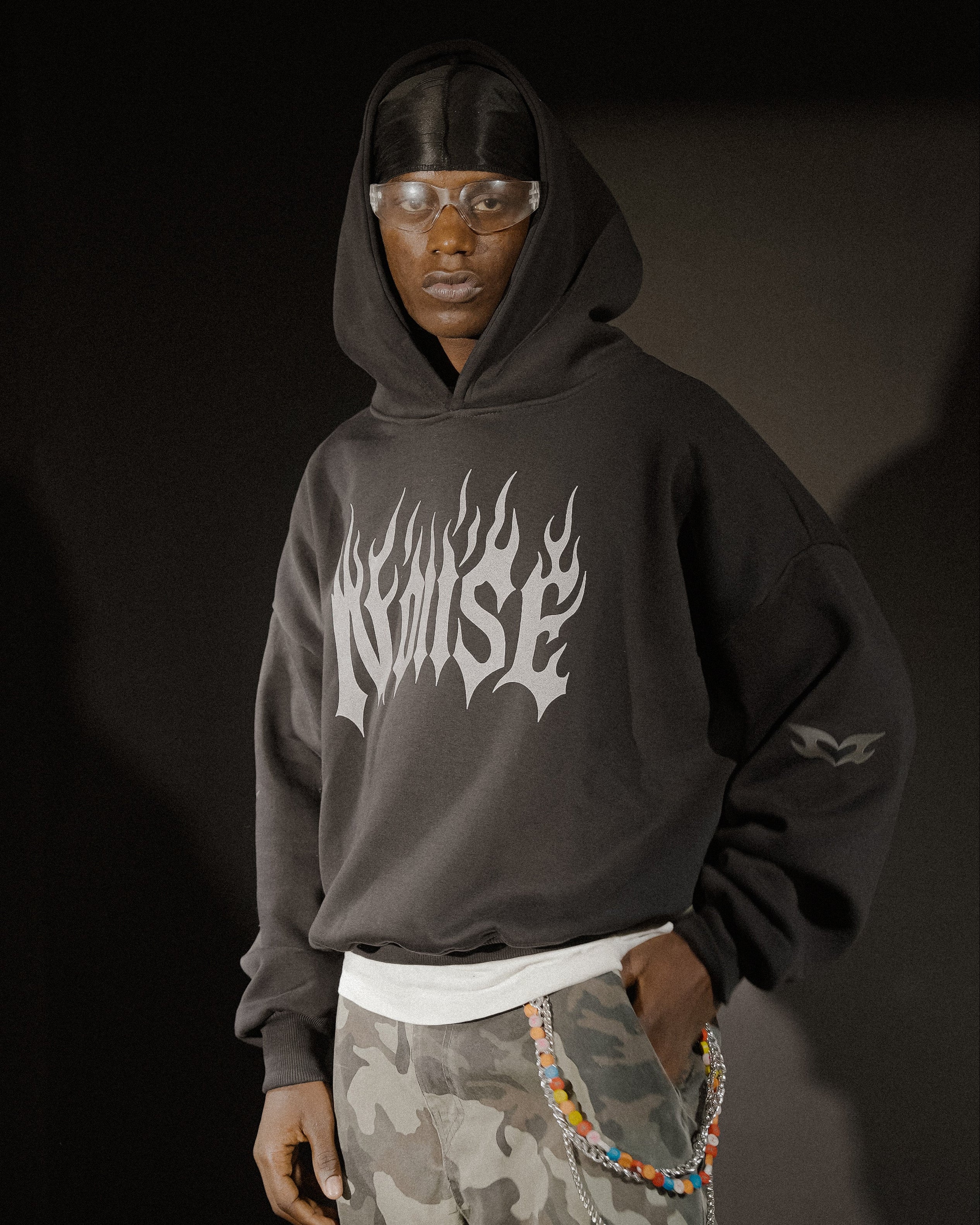 Person wearing a black hoodie with white text, standing against a dark background