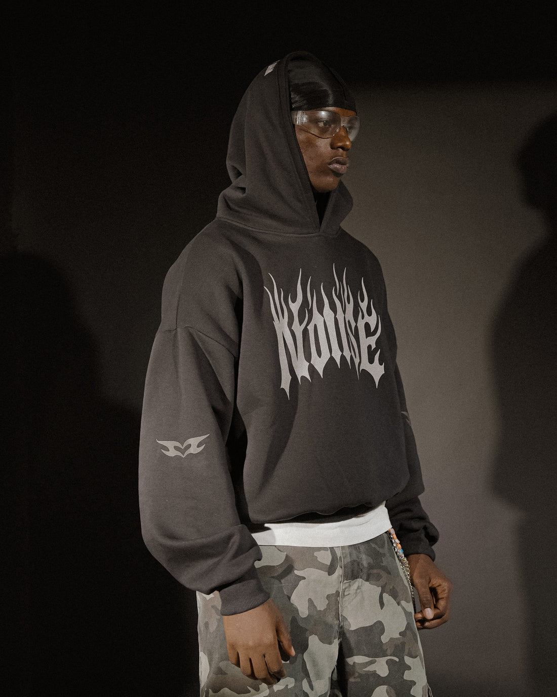 Person wearing a black hoodie with 'Nunrise' logo and camouflage pants on a dark background