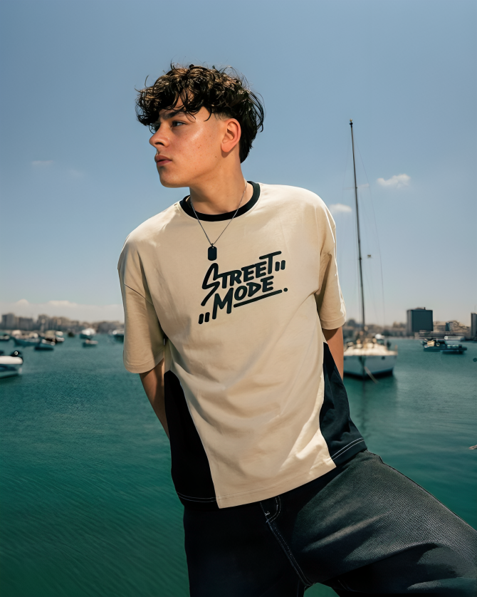 Person wearing a 'Street Mode' t-shirt by a waterfront with boats and buildings in the background.